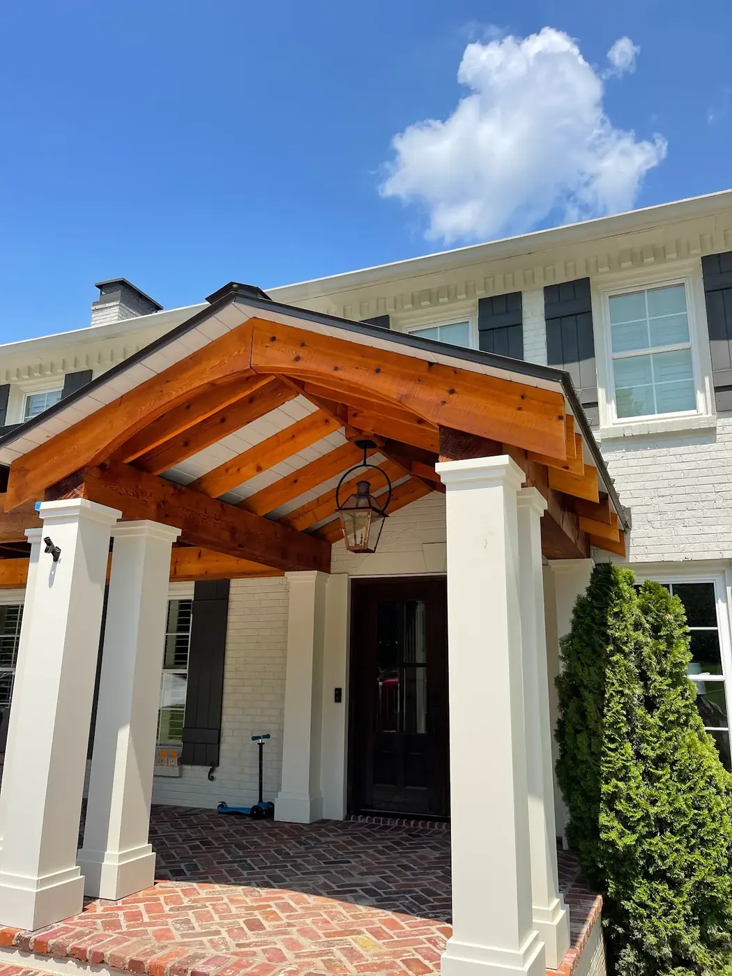 White painted brick home with stained cedar portico beams in Middle Tennessee